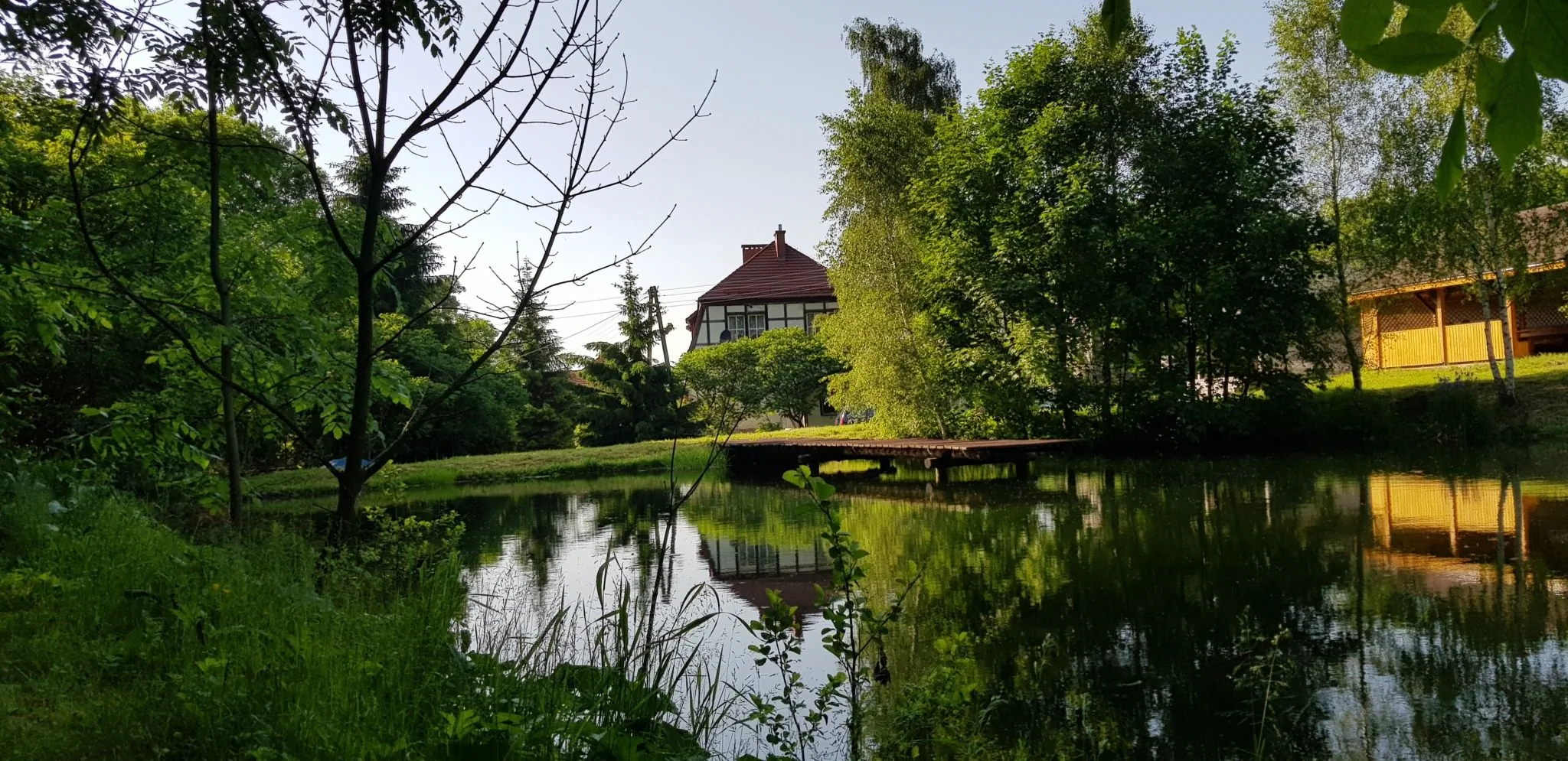 Otoczenie - widok na staw, z budynkiem gł&oacute;wnym w tle