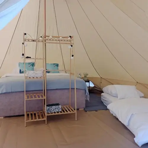 Wnętrze namiotu z ł&oacute;żkiem king-size i dwoma pojedynczymi materacami