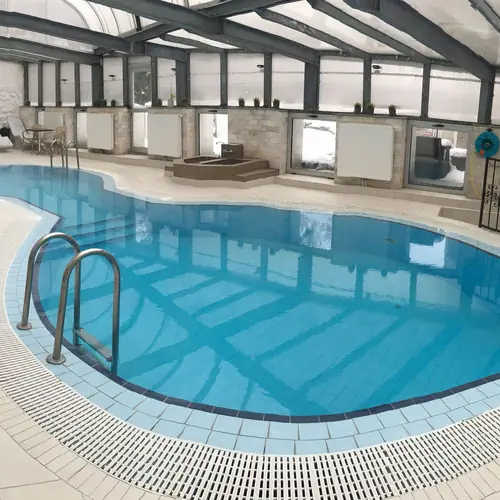 Tetővel fedett &uacute;sz&oacute;medenc&eacute;nk, a nagyszauna bej&aacute;rat&aacute;val a h&aacute;tt&eacute;rben.