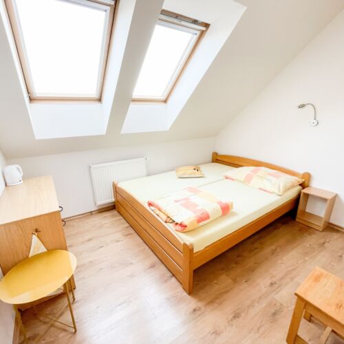 Pokoj s manželskou postelí s výhledem do dvora v podkroví